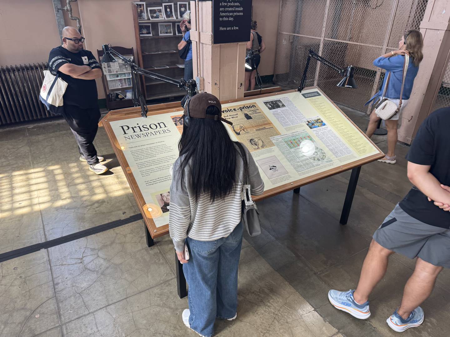 A visitor standing at the title panel in the cellhouse, reading it under the lamp