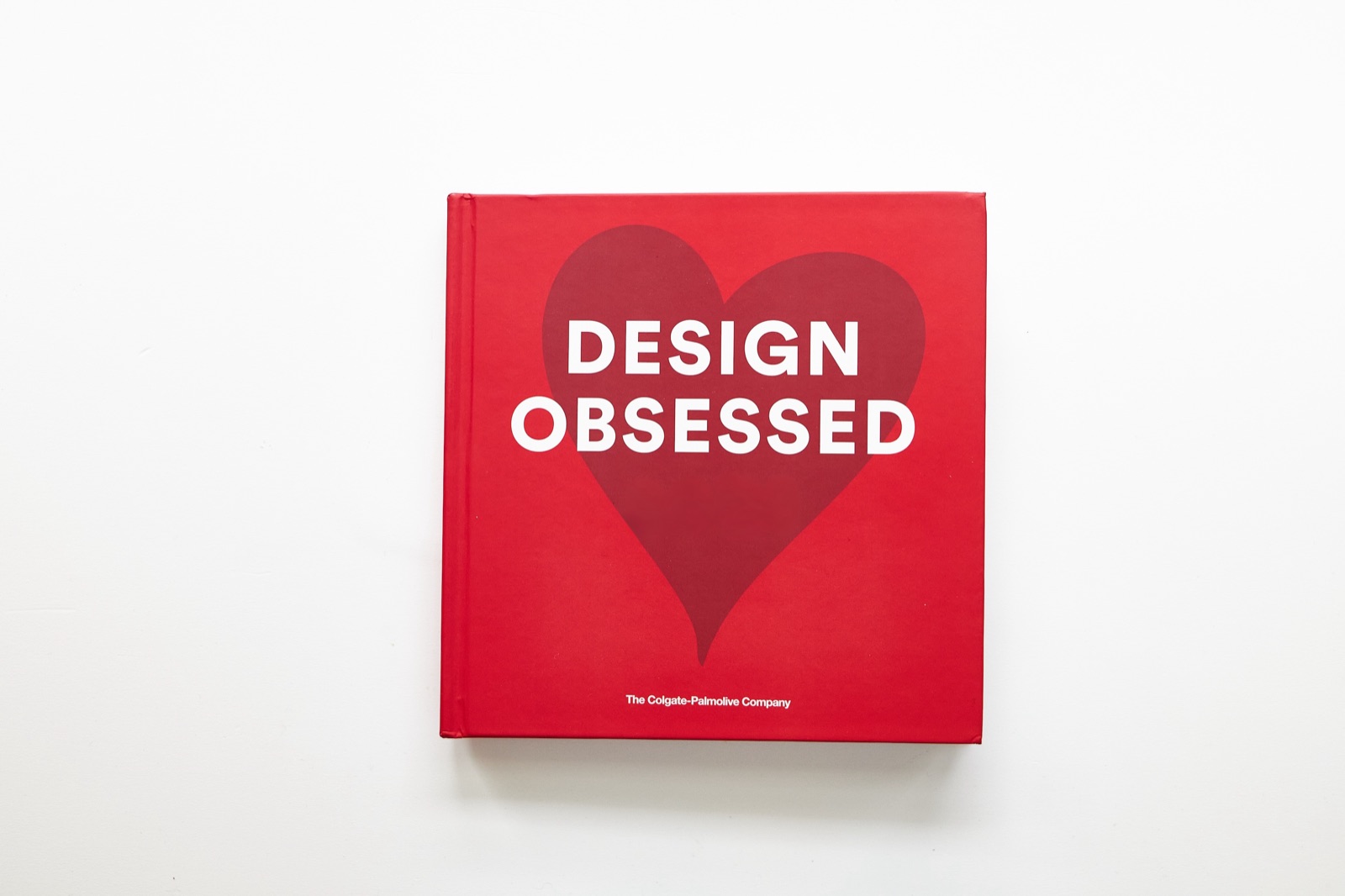 The printed book: a red hardcover titled Design Obsessed, with a heart on the cover, photographed on a white table